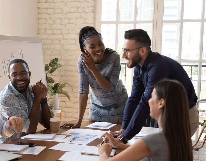 Happy friendly multiracial business team laughing working together at corporate briefing gathered at table